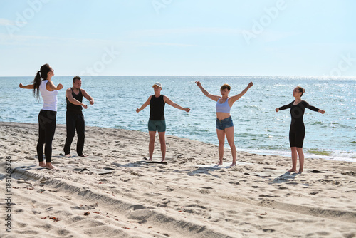 Group yoga session on Sunny Baltic Sea Beach with five adults