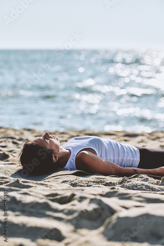 Young woman practicing mindfulness yoga lying on Baltic Sea beach