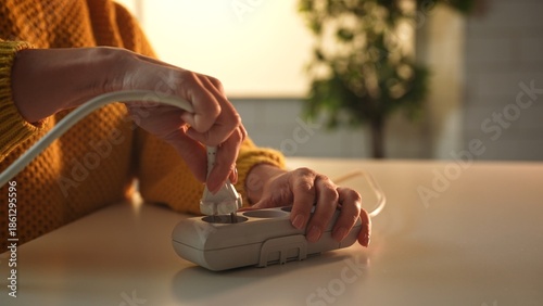 Cuadro en lienzo Close up of hands inserting a power plug into a surge protector on a table, with a blurred background