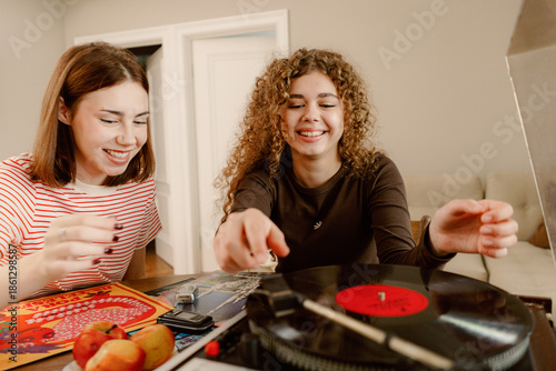 Fotografi Two young women share joyful moments as they spin vinyl records in a cozy living room
