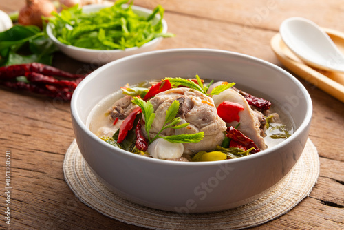 Spicy and sour clear soup chicken and young tamarind leaves in white bowl.