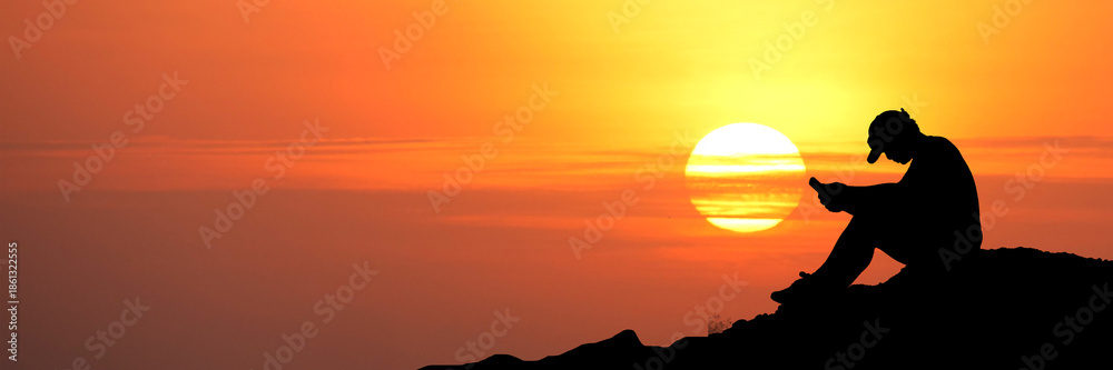 custom made wallpaper toronto digitalA silhouette of a person using a phone during a warm sunset or sunrise. The sun is a bright ball of fire in the sky, creating a beautiful and dramatic scene. 