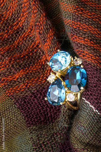 Close-up of a blue gemstone ring set against textured woven fabric.