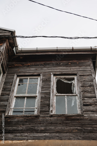 Abandoned wooden facade of the weathered house with broken window