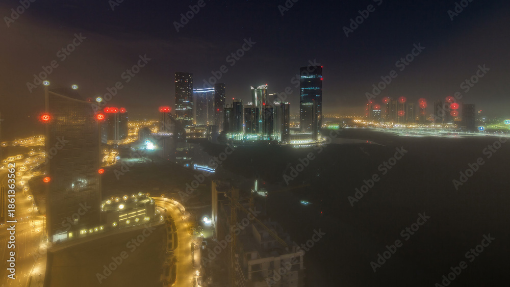 Fototapeta premium Buildings on Al Reem island in Abu Dhabi night timelapse from above.