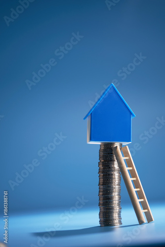 Step ladder and house model on top of stack of coins