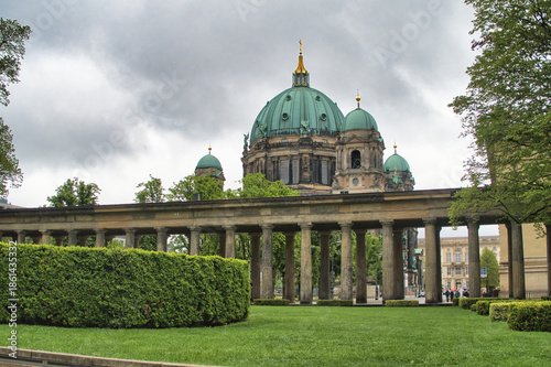 Tablou pe pânză Berlin Cathedral View from Lustgarten Colonnade - The majestic Berlin Cathedral (Berliner Dom) viewed from the Lustgarten park, framed by a classical colonnade and manicured green hedges