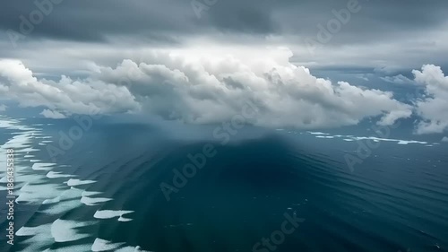 Aerial view of ocean waves and dramatic clouds under overcast sky