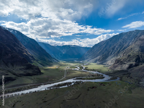 Scenic view of Chulyshman River Valley in Altai. lush green vegetation and towering mountains under cloudy sky. Travel and landscape photography.