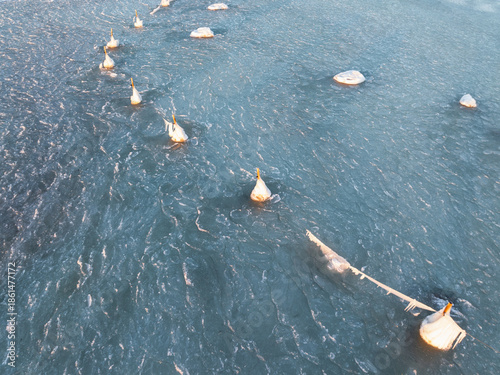 Aerial view of frozen navigation buoys covered in thick ice and icicles in the Baltic Sea, Pärnu bay, Estonia.