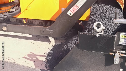 Fresh asphalt is being laid by road construction paving machine on urban development.