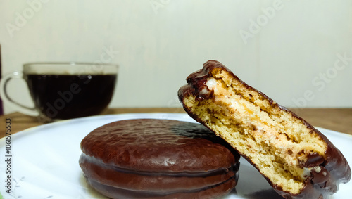 Extreme close-up focusing on the texture of a chocolate-covered marshmallow pie with a bite mark, revealing the soft cream inside.