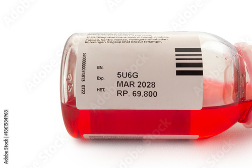 Close-up shot of a pharmaceutical liquid medicine bottle with a focus on the label showing the expiration date, batch number, and retail price.