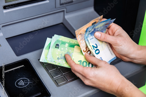 Photos Hands of a person withdrawing cash from an ATM, showcasing various euro banknote
