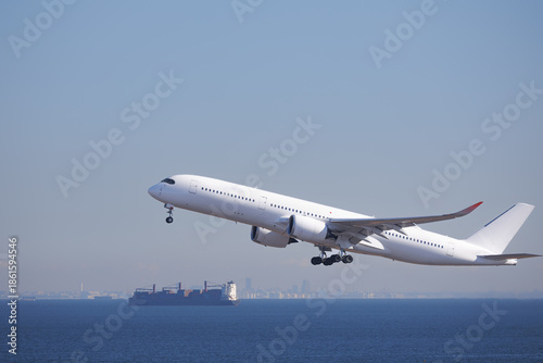 羽田空港、空に舞い上がる旅客機と沖を航行する貨物船