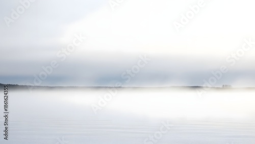 A serene lake scene with foggy clouds reflecting on calm water from a distant viewpoint