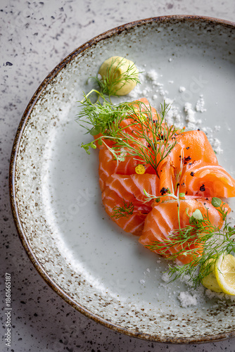 Elegant gravad lax dish with thinly sliced cured salmon marbled texture dill mustard sauce and lemon on refined ceramic plate  
