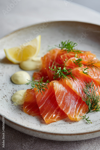 Elegant gravad lax dish with thinly sliced cured salmon marbled texture dill mustard sauce and lemon on refined ceramic plate  
