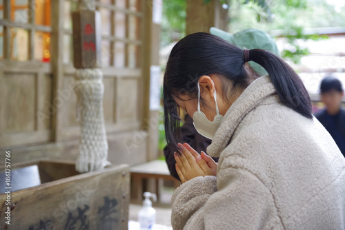 神社で手を合わせて祈る若い女性