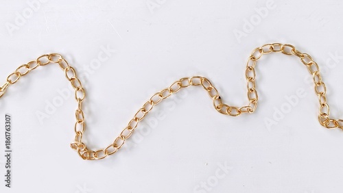 Wavy gold cable chain path laying flat on white background.