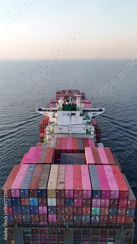 4K Vertical back view above large container cargo ship traveling over the ocean