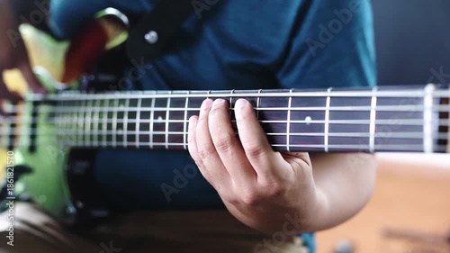 Close-up of bassist playing electric bass guitar in music studio