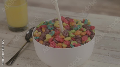 Fresh milk poured into a colorful cereals for breakfast