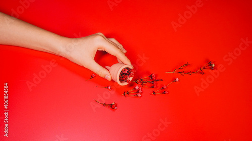 Menstrual Cup with Red Flowers on Red Background Concept Period Flow