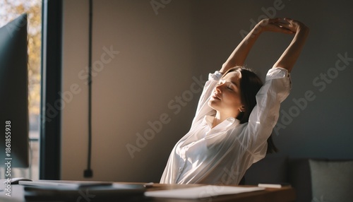Young Woman Stretching Arms Upwards While Sitting at Desk