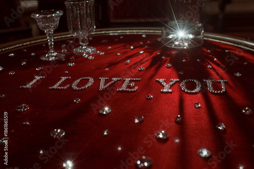 Romantic Crystal Decor on Red Velvet. Red table with crystals forming 'I Love You,' ideal for romantic occasions or Valentine's Day-themed designs.