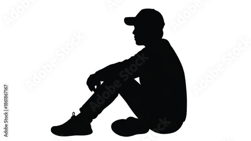 Silhouette of a young man wearing a baseball cap sitting down