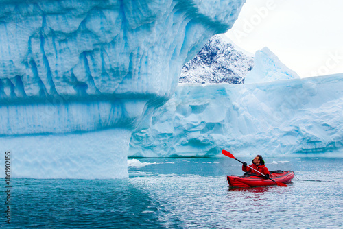 Fotografie kayak adventure expedition in Antarctica, man paddling on red kayak between iceb