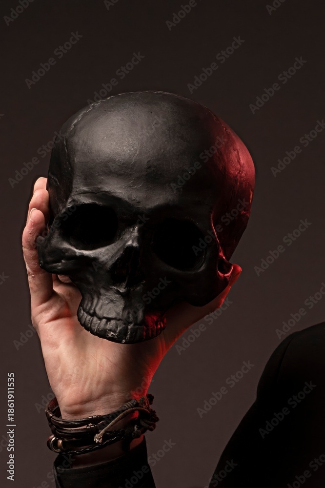 custom made wallpaper toronto digitalClose up of a hand holding a matte black human skull prop with dramatic red accent light