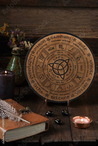 Mystic Wheel of the Year with runes and ritual items on a wooden table. Spiritual and pagan concept.