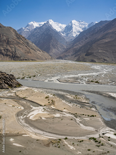 Vertical landscape view of Hindu Kush snowcapped peaks and Panj river on Afghanistan side of Wakhan Corridor, Gorno-Badakhshan, Tajikistan Pamir