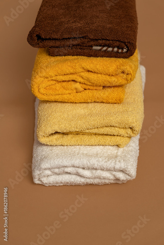Three cotton bath towels neatly folded on a beige background. Concept of cleanliness, natural materials and washing.