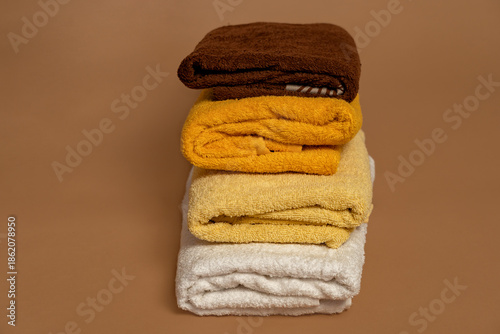 Three cotton bath towels neatly folded on a beige background. Concept of cleanliness, natural materials and washing.