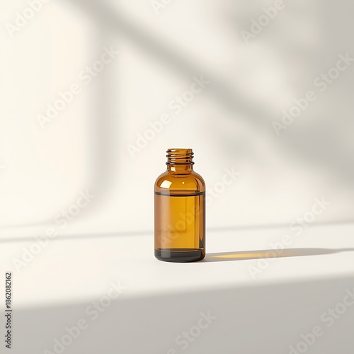 A small amber glass bottle with a clear liquid sits on a white surface, casting a shadow.