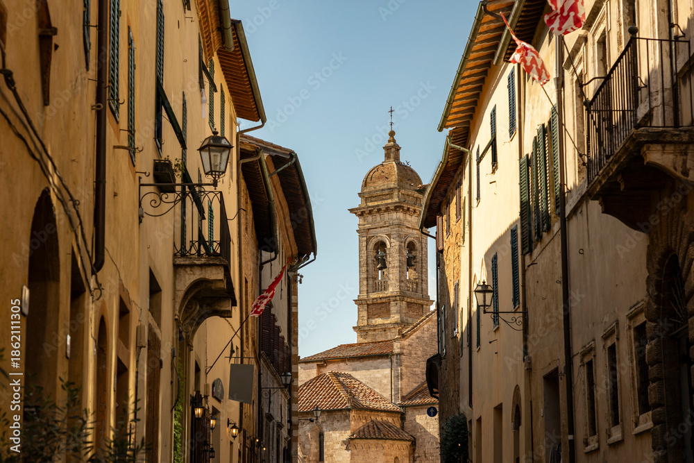 Fototapeta premium street at dusk with a view to the church in San Quirico d'Orcia, Province of Siena, Tuscany, Italy