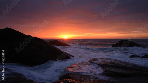 Ocean waves crashing against rocky shoreline at sunset