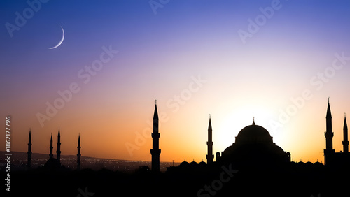 A majestic mosque silhouette against a vibrant twilight sky with a crescent moon