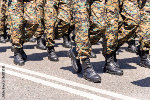 Foto A group of soldiers marches in military camouflage trousers and black boots on an asphalt road