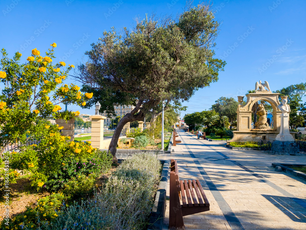 Obraz premium Valletta park promenade with historic fountain and bust in the old town