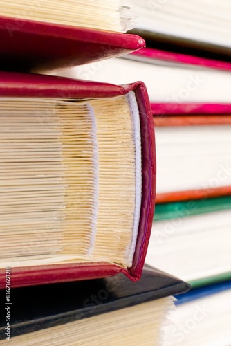 Stack of hardcover photo albums with red covers, macro view of album spines and pages.