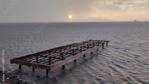 The sun peeking through the clouds after a rainy day, and the abandoned, broken pier.