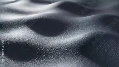 Close up of flowing dark gray fabric with soft dramatic light and shadow