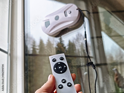 Fotografía Robotic window cleaner in use indoors while a person controls it by hand for eff