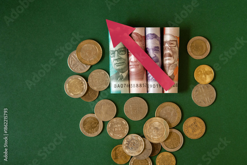 Concept of rising inflation with Colombian peso banknotes and coins and an upward arrow. Minimum living wage