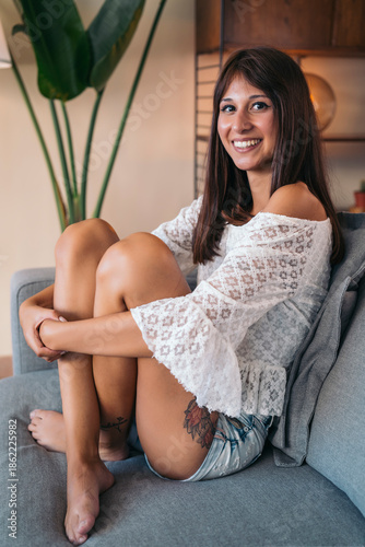 Young woman smiling sitting on sofa lifestyle portrait