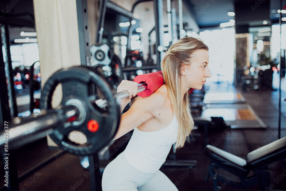 Fototapeta premium Athletic girl doing weighted squats for leg and glute strength training